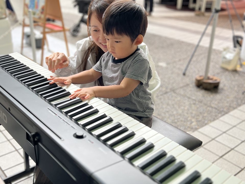 お母さんと一緒にピアノの鍵盤に触れる男の子