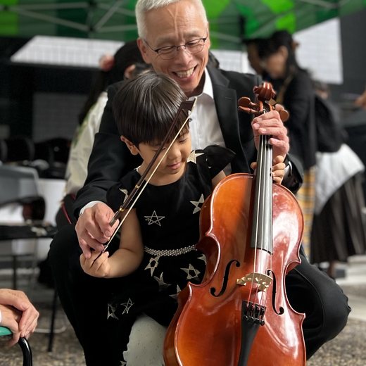 先生のひざの前でチェロを弾く子ども