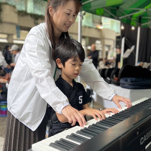 先生と一緒に電子ピアノを弾く男の子